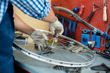 Male hands in textile gloves fixing bolt on central part of bicycle wheel