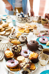 Homemade pastry and drinks on served table with man cutting cake on background