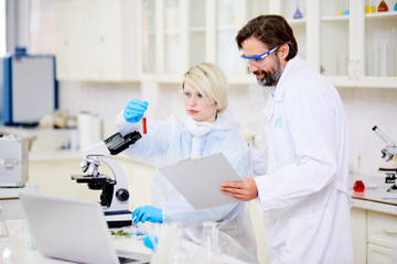 Scientists in uniform analyzing chemical compound in lab