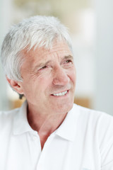 Senior man with toothy smile and grey hair staring aside at something curious
