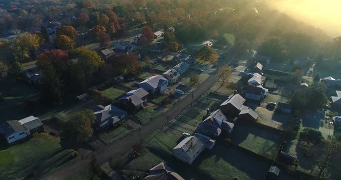 A slow reverse aerial establishing shot of a typical Western Pennsylvania residential neighborhood on a foggy late-Autumn morning. Pittsburgh suburbs. Shot at 60fps.  	