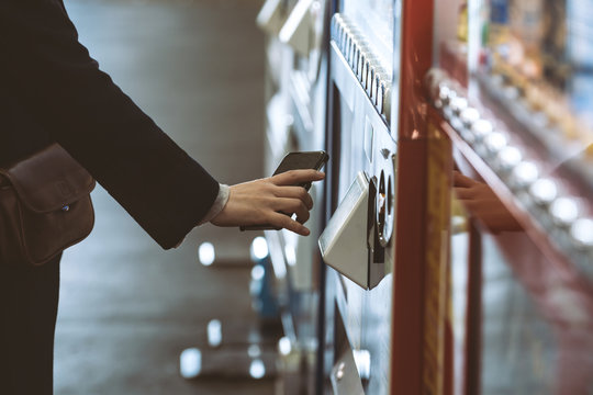 自動販売機で電子マネーを使う女性