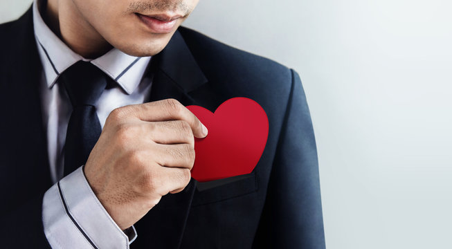 Customer Services Concept, Businessman Dropping a Heart (paper card) in his Pocket with Carefully