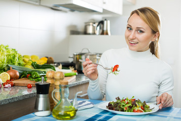 Obraz na płótnie Canvas Happy girl with vegetable salad in kitchen