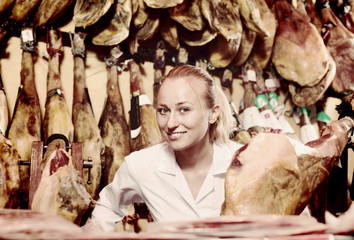 Closeup of cheerful woman seller showing iberian jamon
