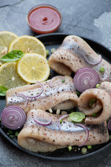Herring fillet served with red onion, lemon and spices on a metal plate, selective focus