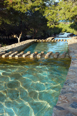 Water pools with waterfalls in a pine park, top view