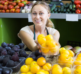 Portrait of happy woman selling ripe fresh plums