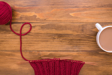 Coffee and red knitting on wooden background