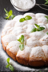 Freshly baked sweet yeast rolls decorated with mint and powdered sugar close-up. vertical
