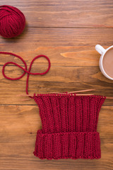 Coffee and red knitting on wooden background