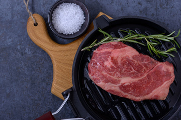 Closeup raw beef striploin steak on grill pan with rosemary
