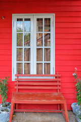Obraz premium Red wood wall, white window and red wood bench