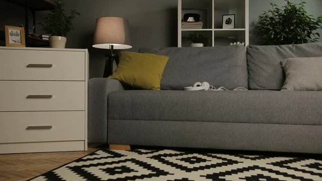 Zoom in. The empty cosy living room with couch, pillows and white headphones. Home interior