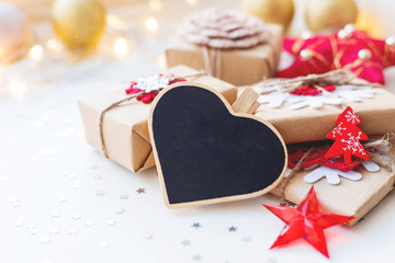Christmas and New Year background with heart chalkboard, presents and decorations for Christmas tree. Holiday background with stars confetti and light bulbs. Place for text.
