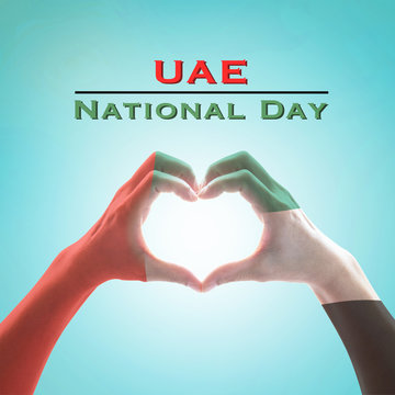 UAE, United Arab Emirate national flag pattern on people's hands in heart shape on blue mint sky background