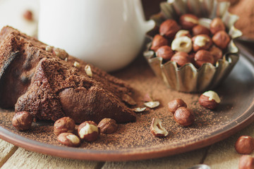 Piece of chocolate cake, hazelnuts and jar with milk