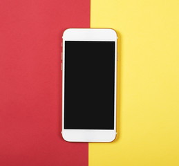 Top view of smartphone on red and yellow background. Technology