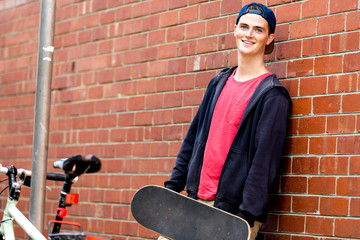 Fototapeta na wymiar Teenage boy with skateboard standing next to the wall