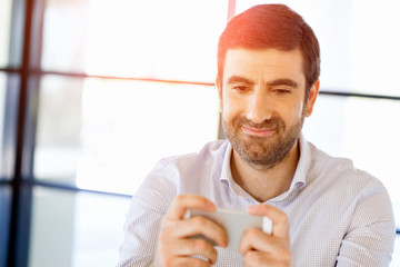 Confident young man in smart casual wear holding phone