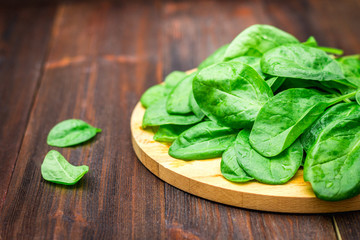 Fresh juicy spinach leaves on a wooden brown table. Natural products, greens, healthy food, vitamins.