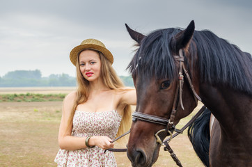 Girl in a straw hat and summer dress, posing with a horse / Photographed in Russia, at the racetrack in Orenburg
