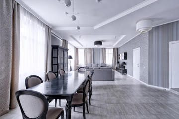 Large dining table in the interior of the apartment in a stylish modern design.