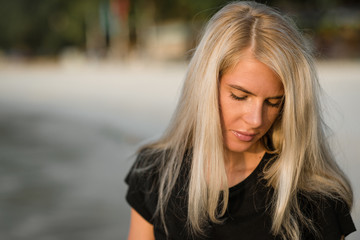 Obraz premium Summer Closeup portrait of beautiful blond girl with long hair and beautiful eyes poses against a beach. Morning walking