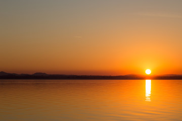 Obraz premium Classic sunset on a lake, with sun low on the horizon