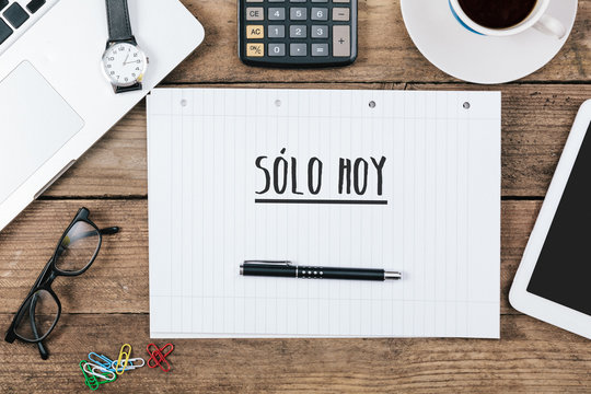 Solo hoy, Spanish text for Only Today on note pad at office desk with computer technology, high angle