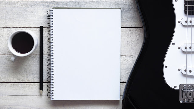Inspirational background with a piano on a wooden table while composing. Score sheet, a pencil and a cup of coffee for the music composer, Top view and a copy space for editor's text.