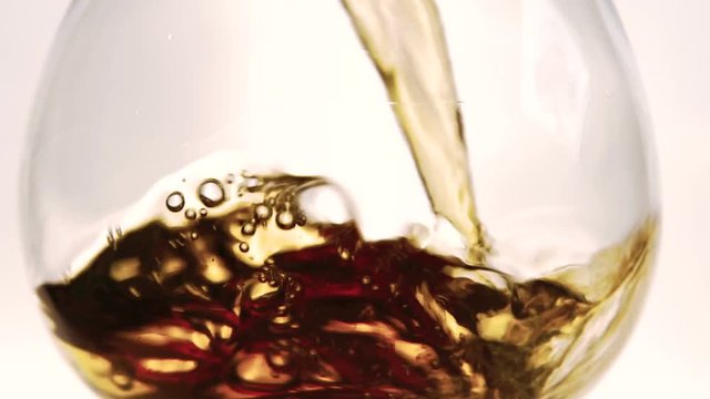 The brandy is splashing and waving in the clean cristal glass while being poured. The liquid is old, luxury and very expensive. Alcohos has wooden brown color with bronze, ginger and golden gradations
