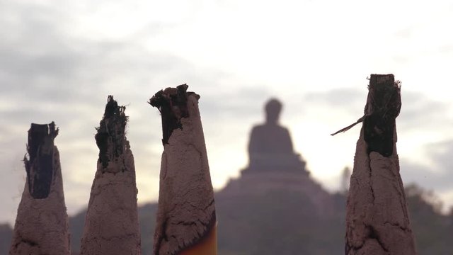 Rauch von Weihrauch-Stangen im Vordergrund,  im Hintergrund die Silhouette einer Buddha-Statue auf Lantau, Hongkong