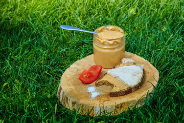 spoonful of peanut butter on wooden plate with meat sandwich