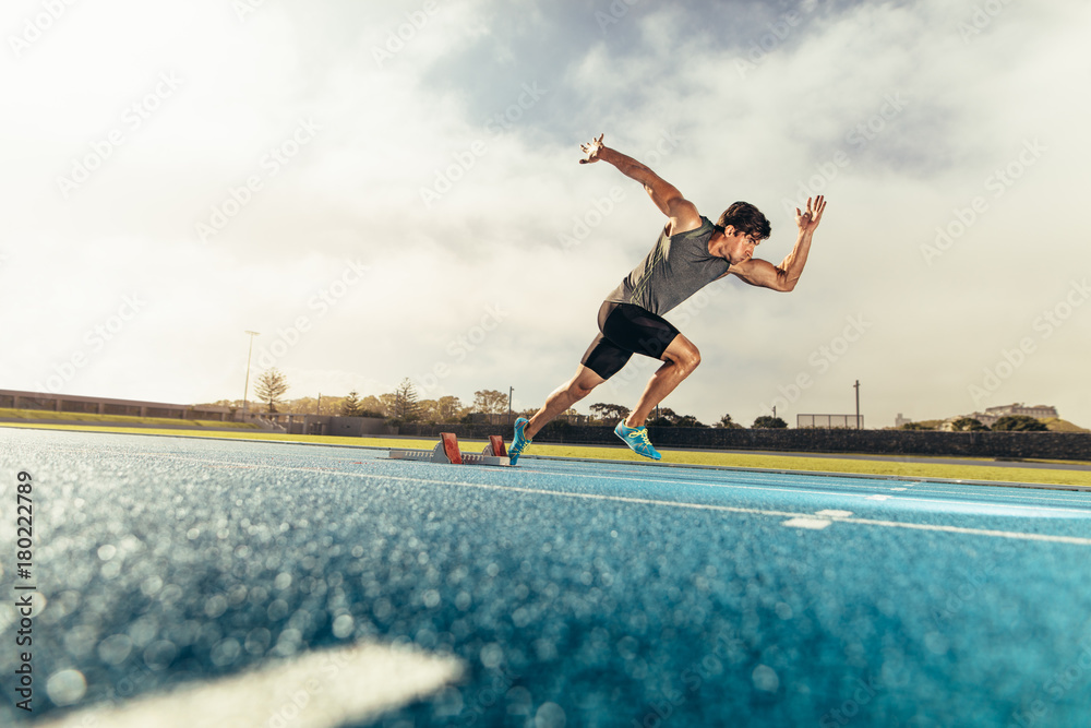 Wall mural sprinter taking off from starting block on running track