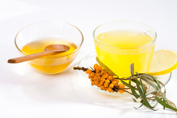 Healing sea-buckthorn tea delicious aromatic full of vitamin and microelements of bright yellow color with berries and leaves of the sea buckthorn fruit on a white background.