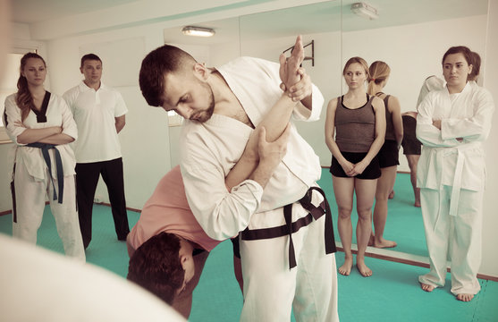 Coach explaining painful hold in taekwondo class