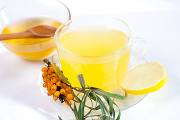 Healing sea-buckthorn tea delicious aromatic full of vitamin and microelements of bright yellow color with berries and leaves of the sea buckthorn fruit on a white background.