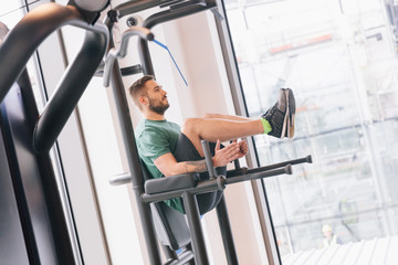 Fototapeta na wymiar Man lifting his legs up on a gym machinery