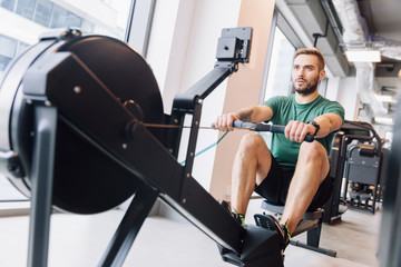 Active athlete man doing rowing workout