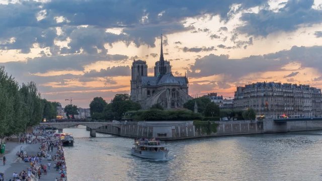 Notre Dame cathedral in Paris, France, against sunset sky. Scenic view over la Cite with fast moving dramatic clouds. 4K Day-night transition timelapse.