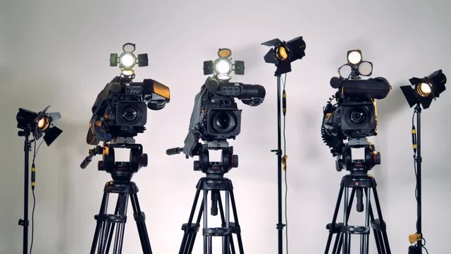 A zooming out shot on three cameras and lighting equipment. 