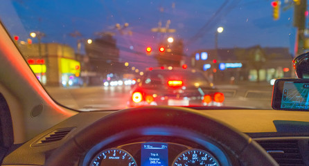 Driving at night on a busy street, car interior view