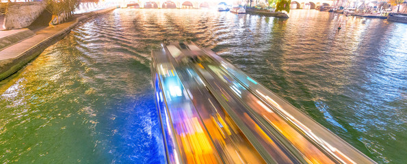 Fast moving ferry boat along Seine river in Paris at night - France