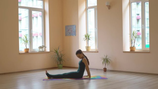 A professional yoga instructor demonstrates a set of healing enhancements for strengthening the muscles of the legs and buttocks. Multiseries video. Young attractive brunette girl is engaged in a