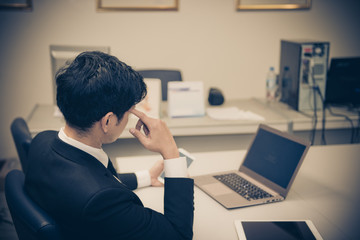 Businessman stress from hard work on the desk at office dark tone