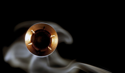 Incoming bullet directed at a scary angle, right at the camera, on a black background with white smoking behind