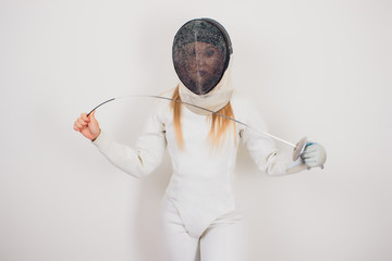 woman wearing fencing suit practicing with sword against grey vignette