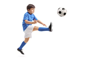 Fotobehang Little soccer player kicking a football in mid-air © Ljupco Smokovski