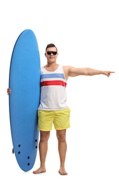 Young man with a surfboard pointing